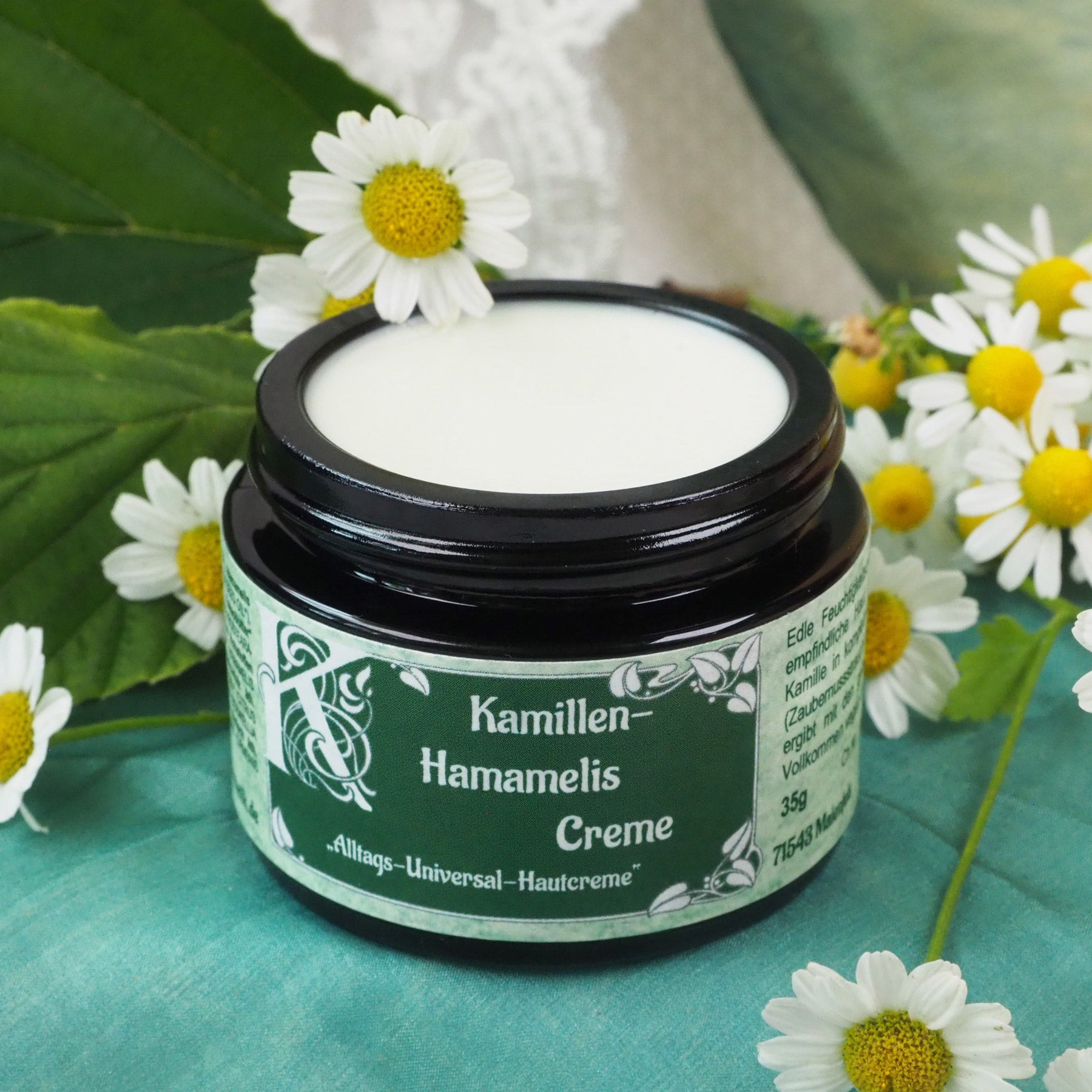 Geöffneter 35ml Kamillen-Hamamelis Creme Tiegel. Kamillenblüten im Hintergrund.