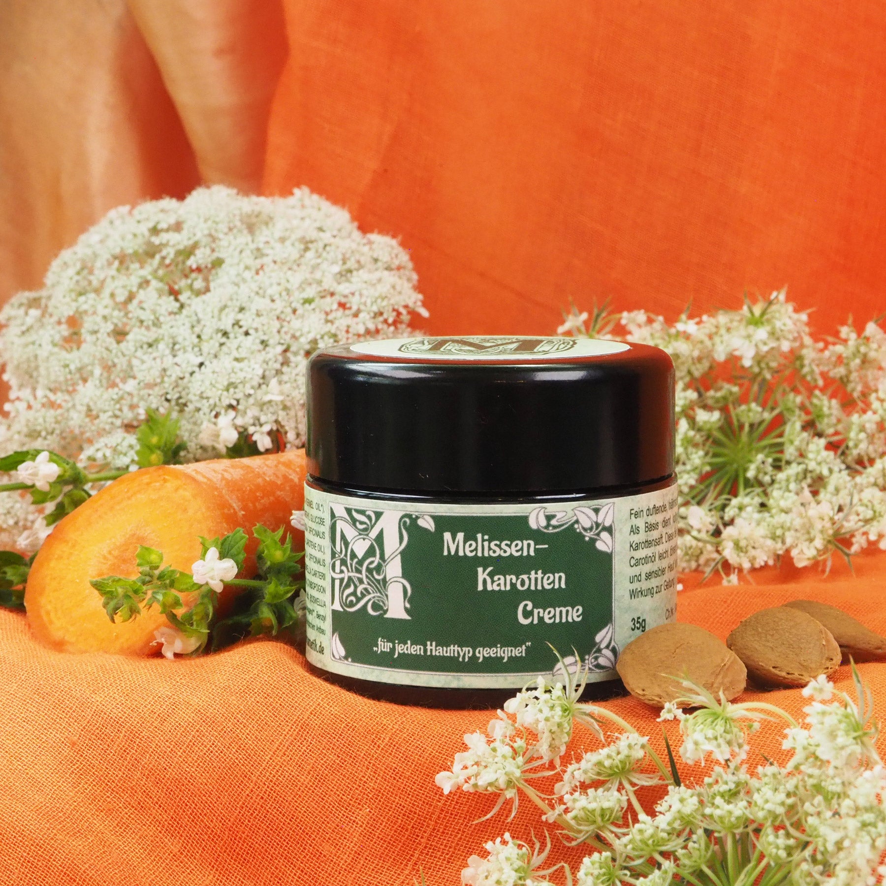 Melissen-Karotten Creme 35ml Tiegel, daneben liegt eine Karotte.